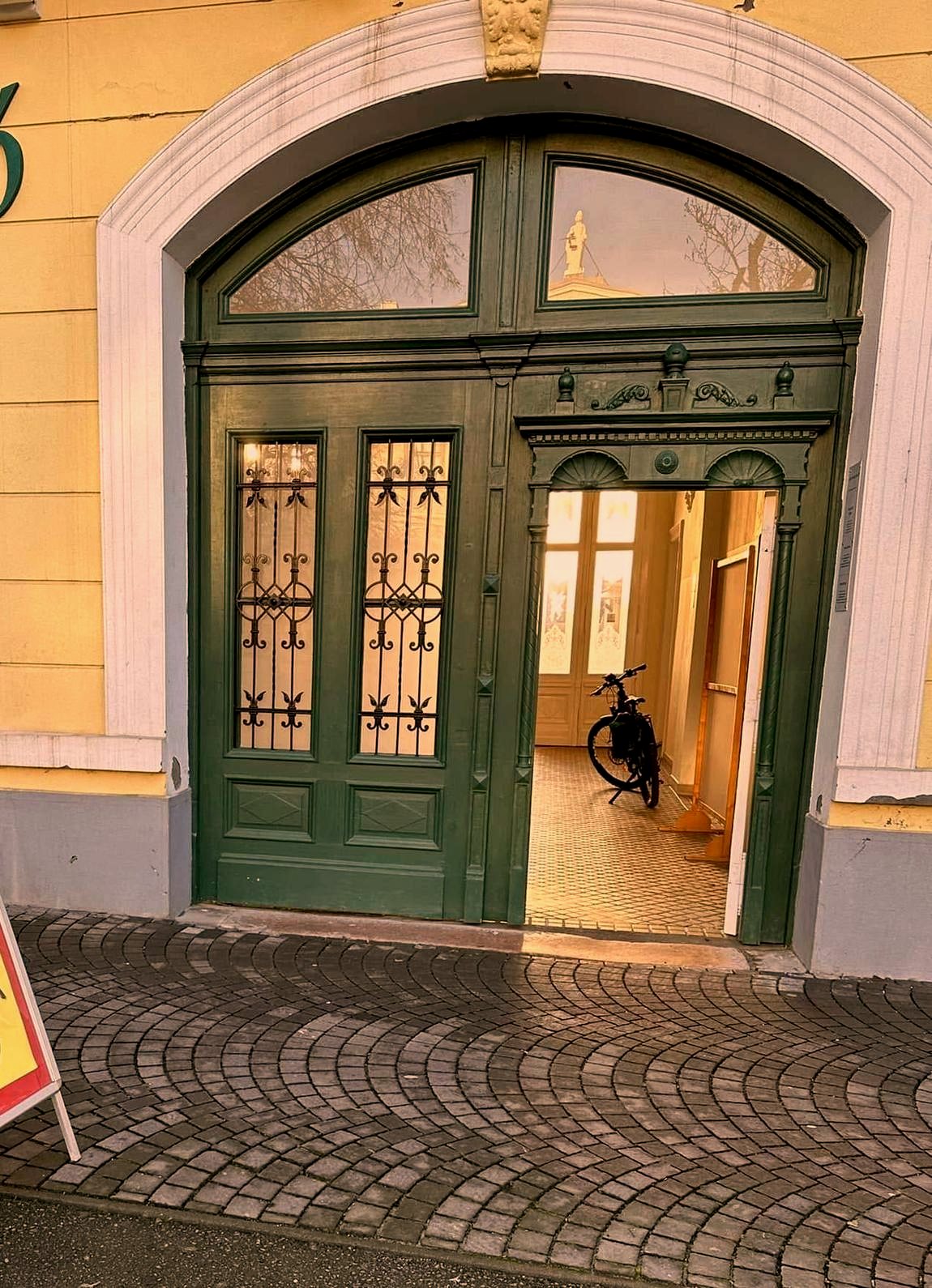 A Bathó Palota boltíves, zöld szárnyas kapuja a Lehel vezér téren, mellette a kézzel festett Pizza Palota tábla