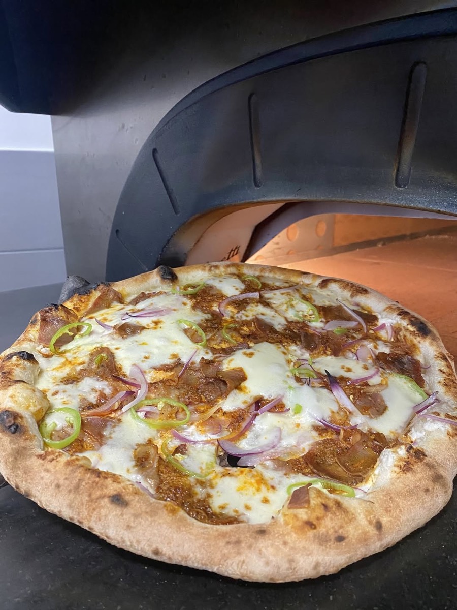 Frissen sült pizza a kemence izzó szája előtt