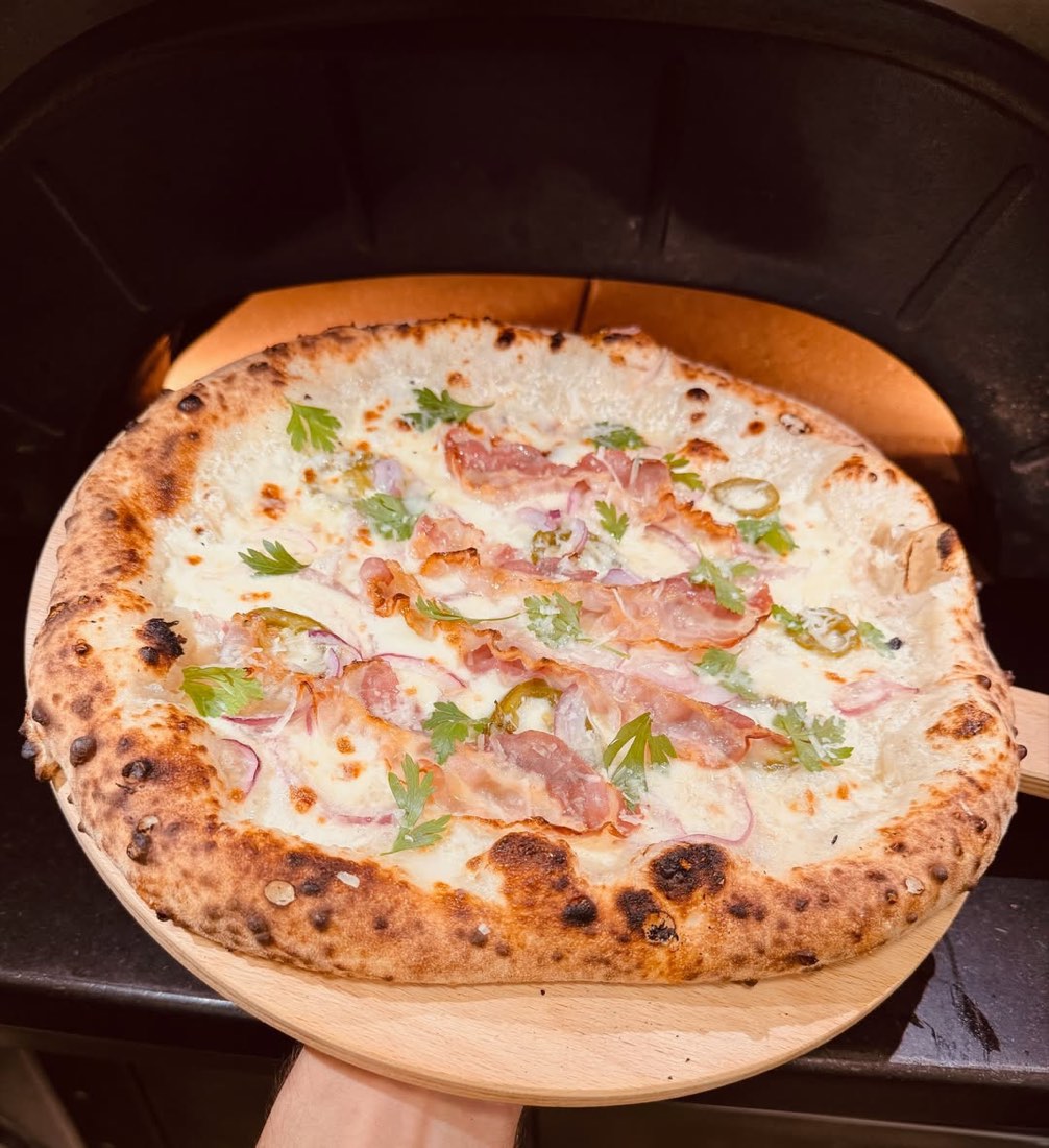 Frissen sült fehér alapú pizza fatálcán, a kemence előtt