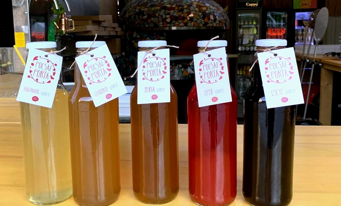 Sorba állított, címkés üvegekben kimért üdítők a pizzéria pultján
